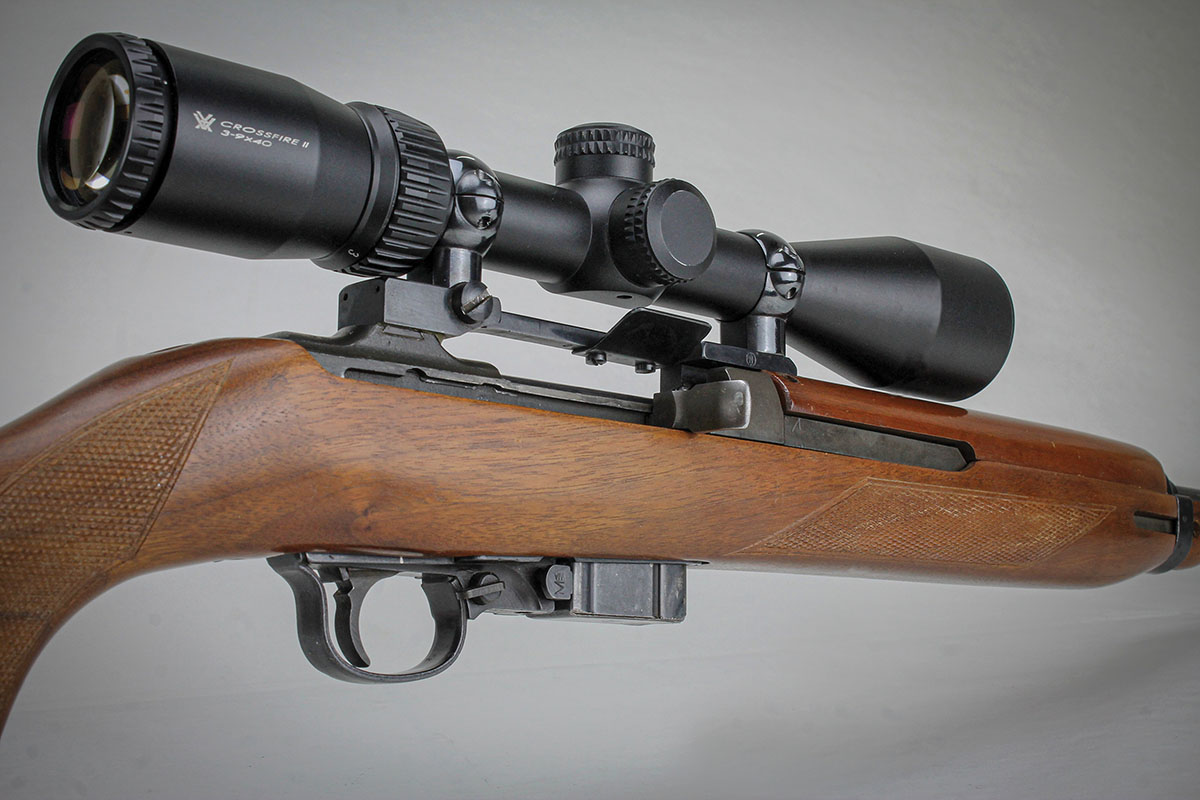 M1 Carbines eject cases almost straight upwards, so some conversions mounted the scope slightly offset to the left side. This centered mount,  however, has a shell deflector to bounce empties down and to the right.